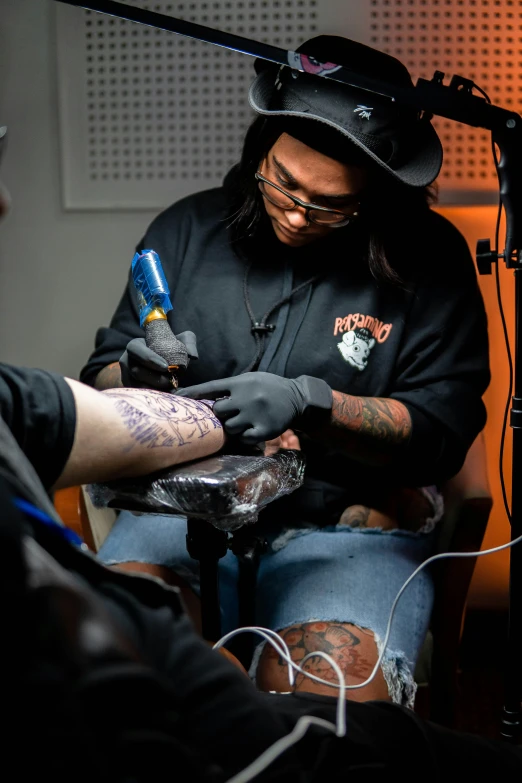 tattooed man in studio recording while holding onto an electric guitar