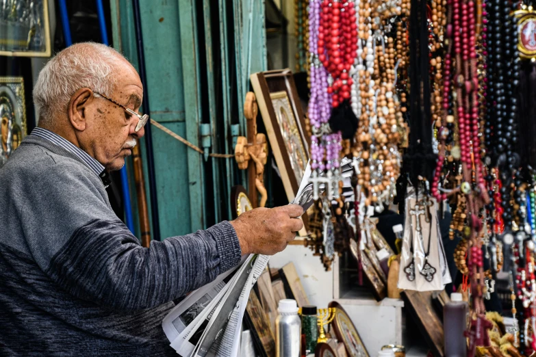 a man looks at a sheet of paper while standing next to a jewelry stand