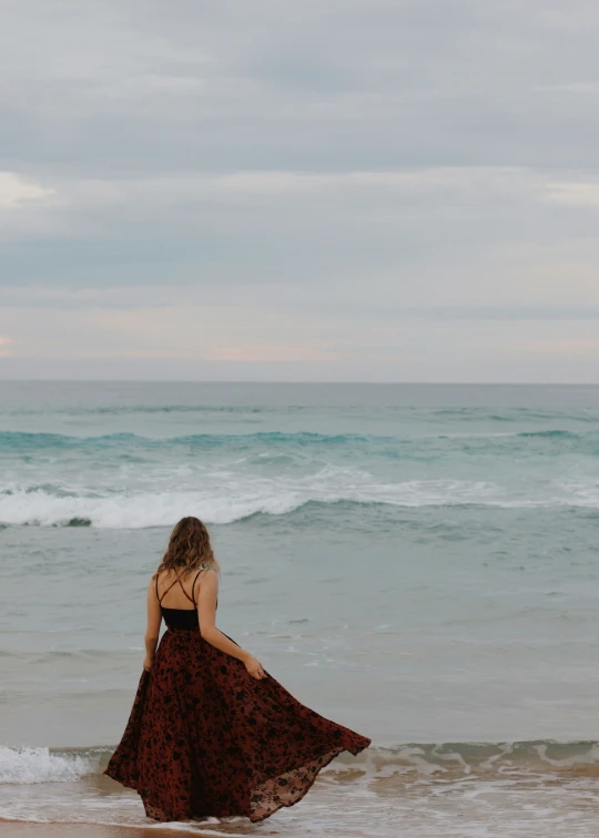 the woman is walking along the beach in the waves