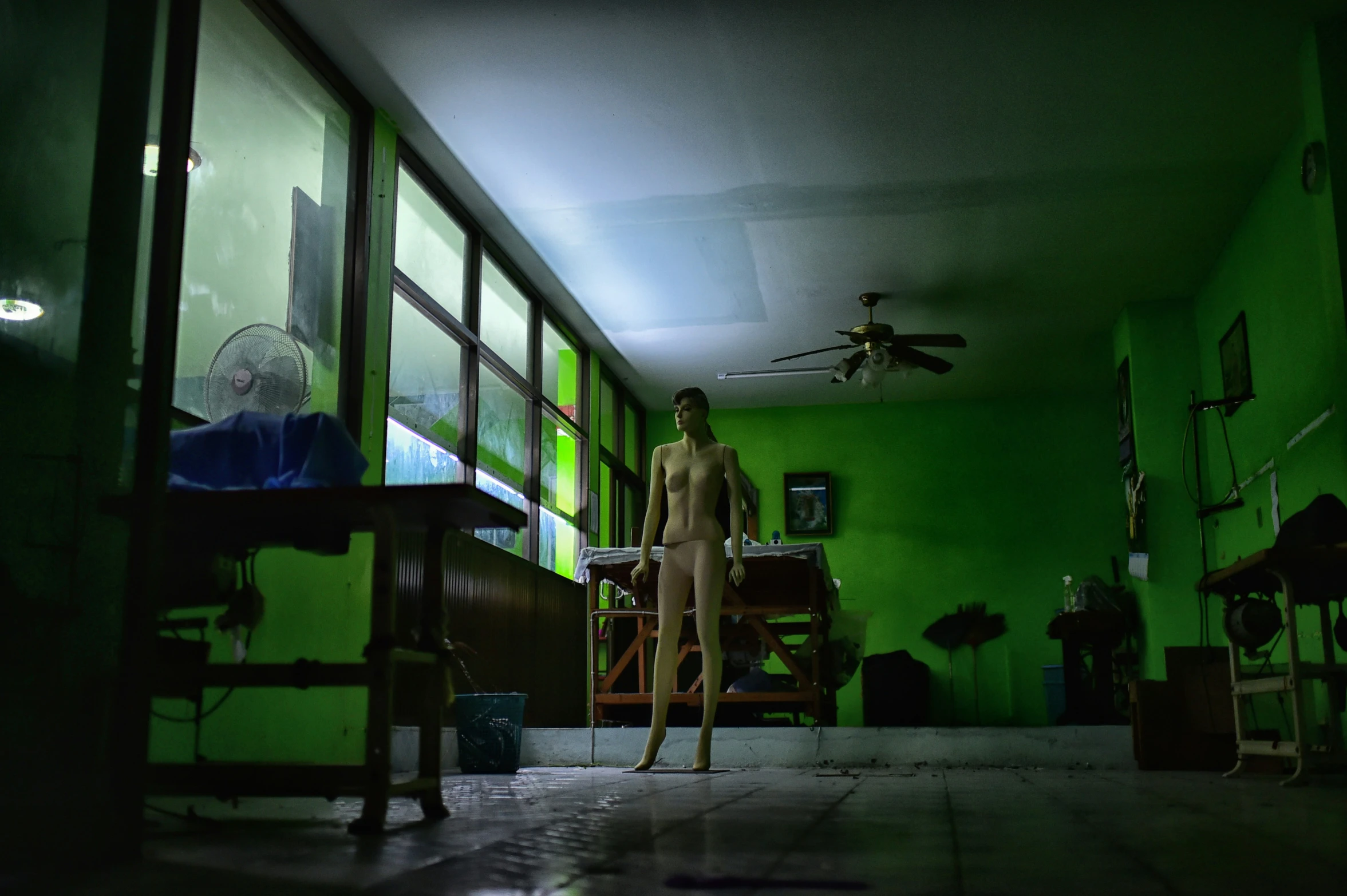 a male figure stands in the living room near a green wall