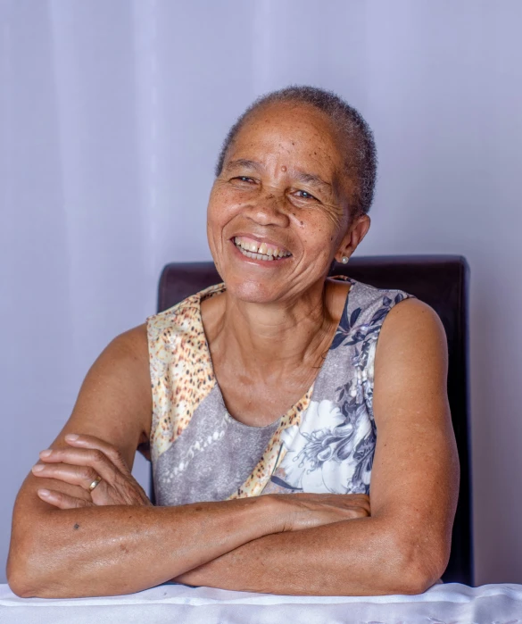 an elderly person sitting at a table with his arms crossed