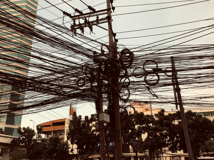 telephone pole covered with wires next to buildings