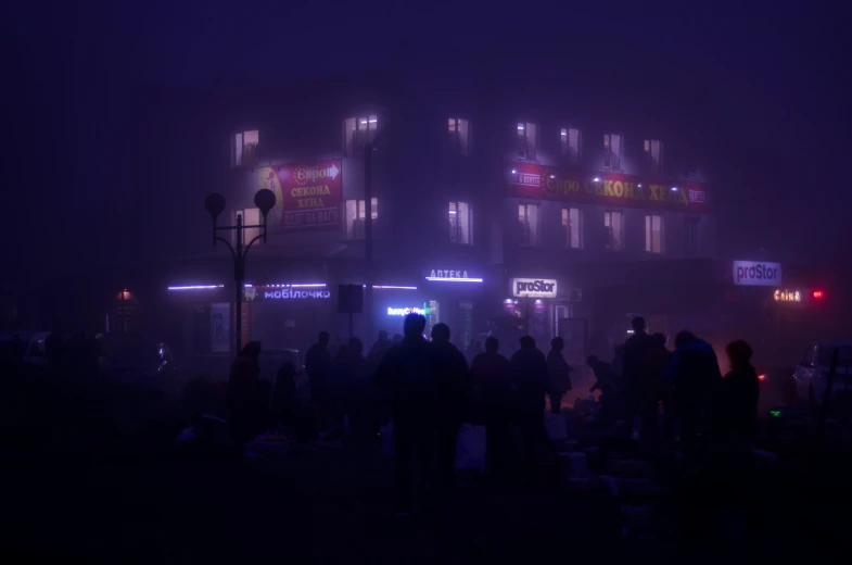 a group of people standing around a city street at night