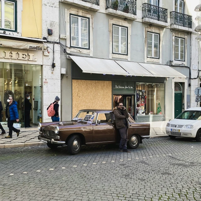 old - fashioned car parked on the side of the road in front of a store