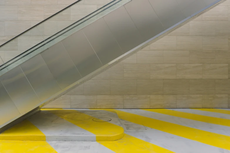 a metal escalator on a tiled floor next to a yellow and white stripe floor