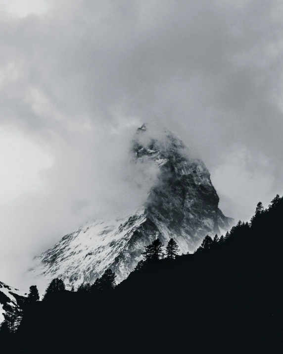 clouds are coming down over the tops of mountains