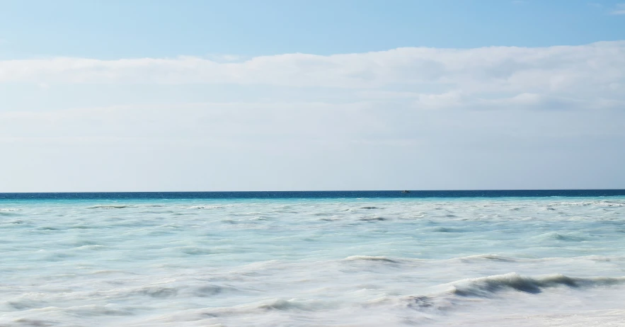 a man para sailing in the ocean under a blue sky