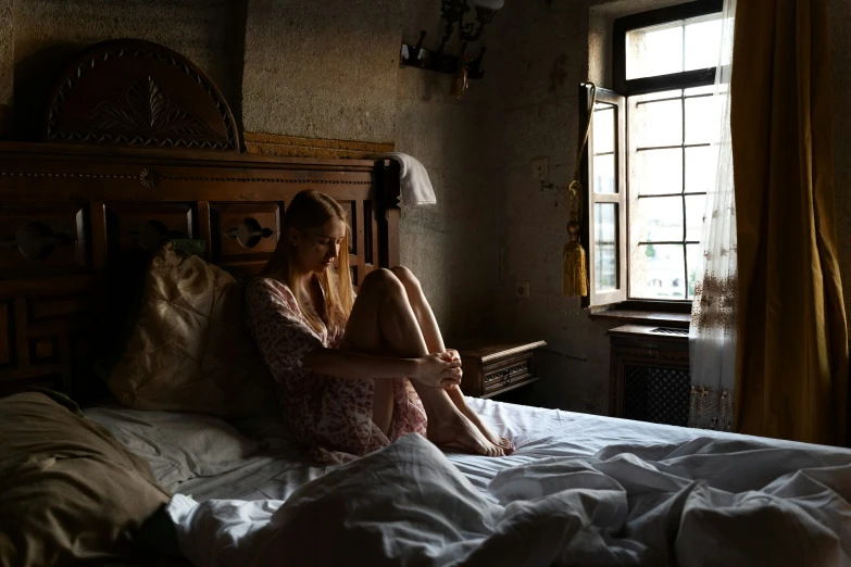 a woman is sitting on a bed with sheets