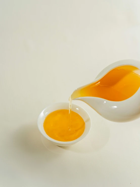 orange juice is pouring into a bowl