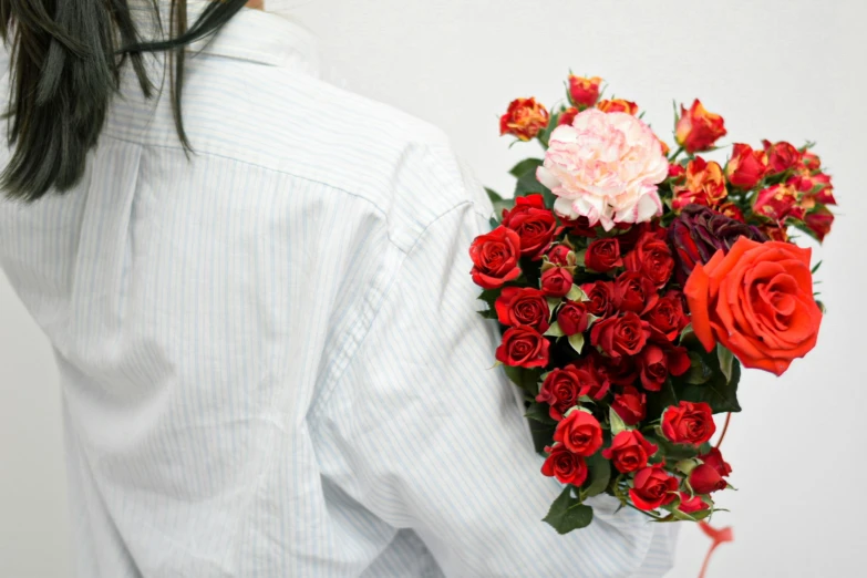 woman wearing white shirt holding bouquet of red and orange flowers