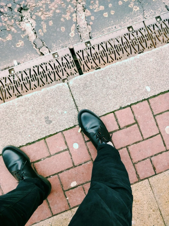 the man in black shoes is standing on the brick road