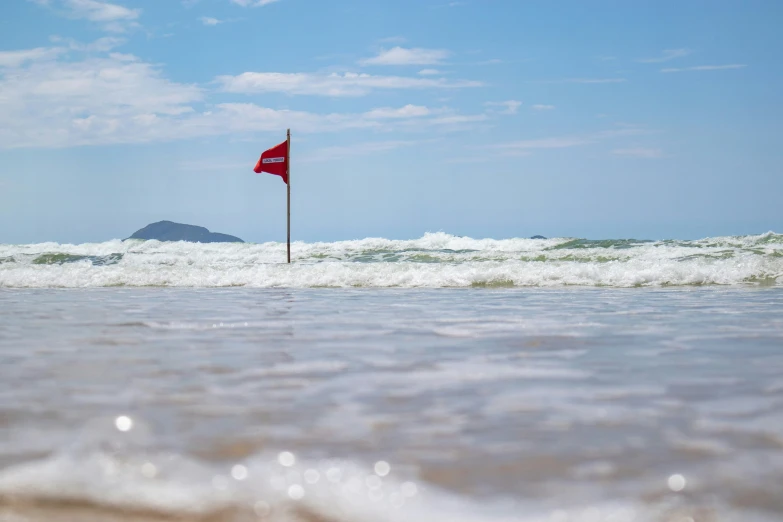 a red flag is standing in the middle of a body of water