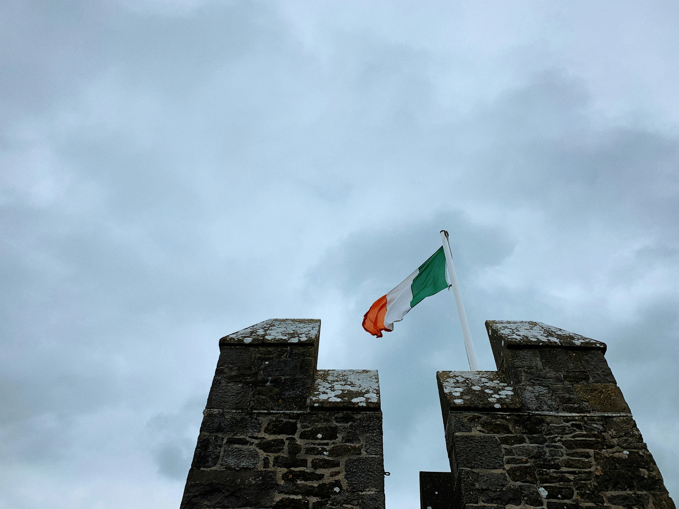 two flags flying from two towers on a cloudy day