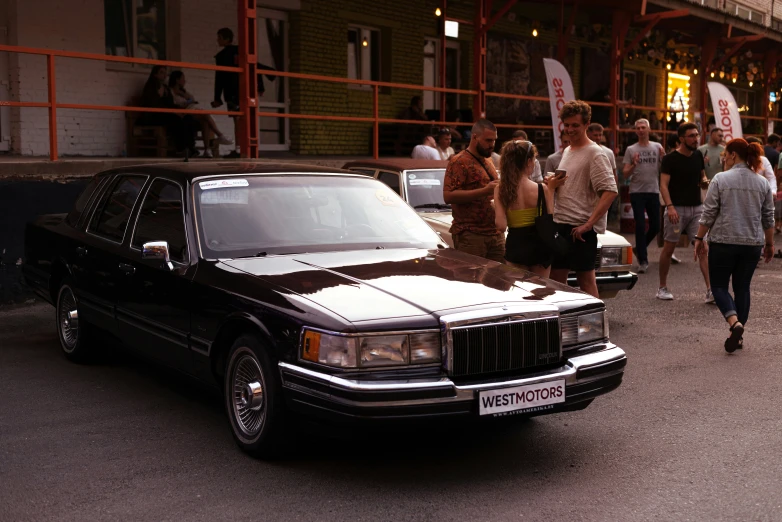 a group of people walk past a car parked near a street