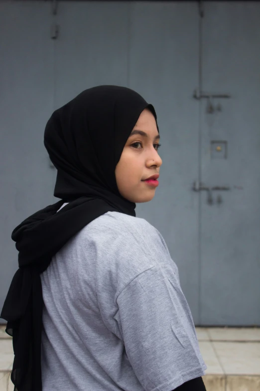 a woman wearing a grey shirt and a black scarf