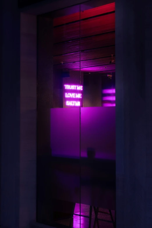 purple neon sign in the corner of a dark room