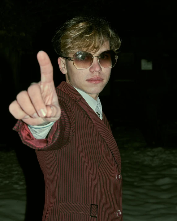 a young man wearing a suit and pointing to the camera