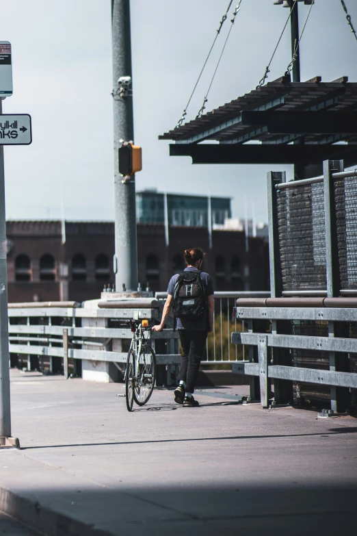 a man stands with his bike at an overpass