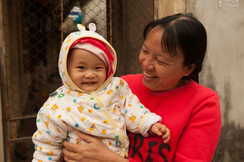 an asian woman smiles and holds a smiling toddler