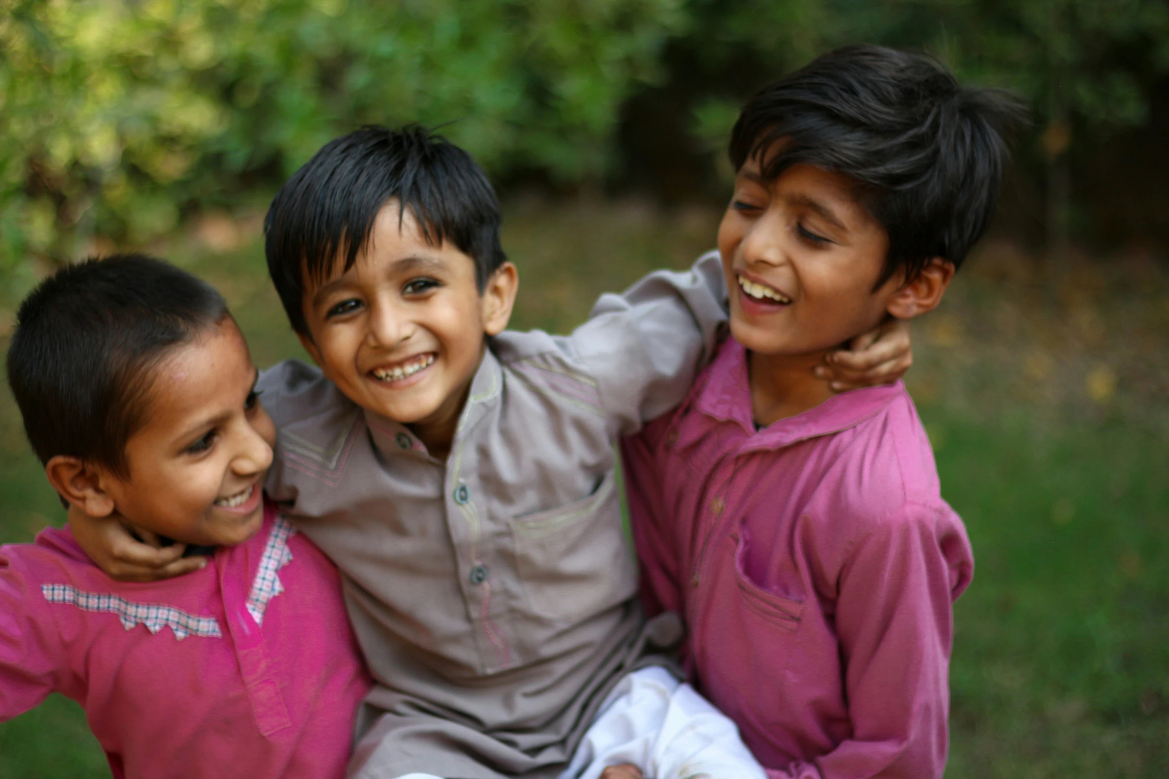 three children sit on the ground together in a field