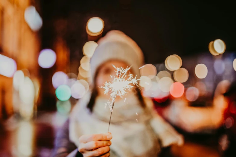 a lady in winter clothes holding a dandelion at night