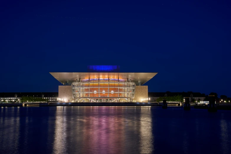 the building is lit up at night from across the lake