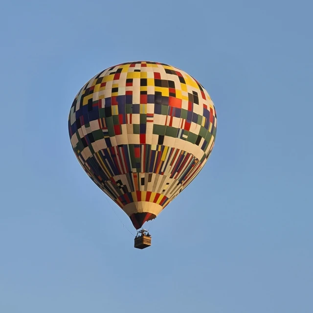 a colorful  air balloon with checkered design floating in a blue sky