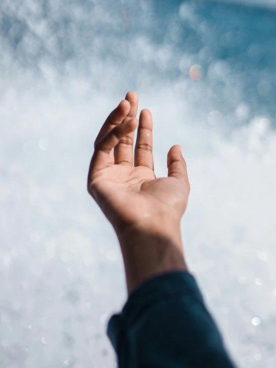 a hand on water with small amount of air in the background