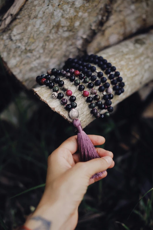 a hand holding a tassel of beads that have been tied together