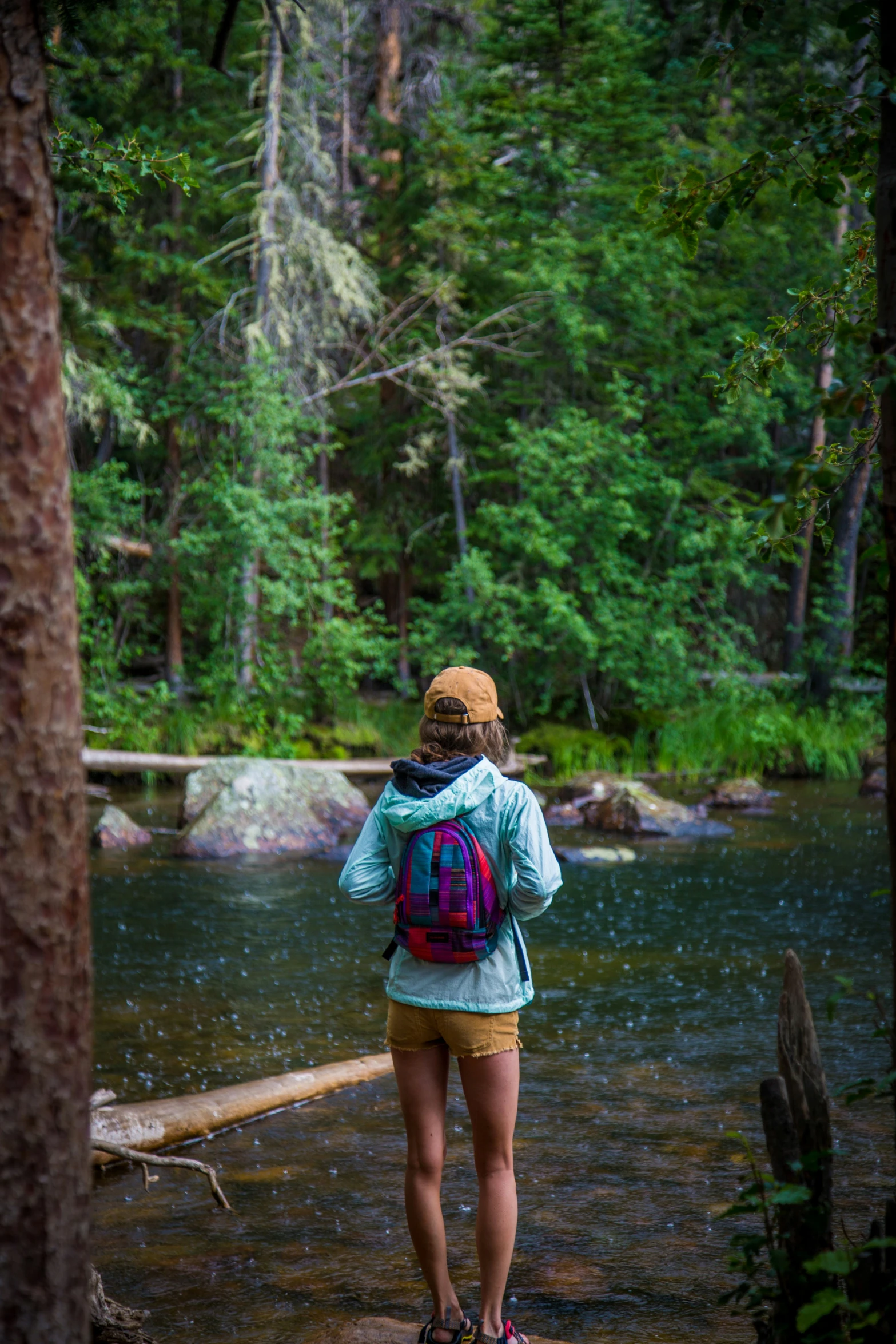 the woman stands near a river while it rains