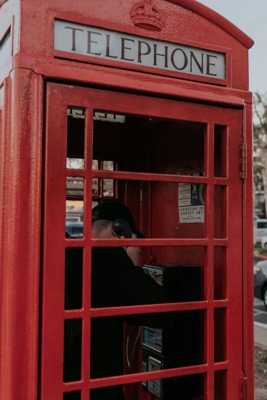 a person sitting inside a red phone booth