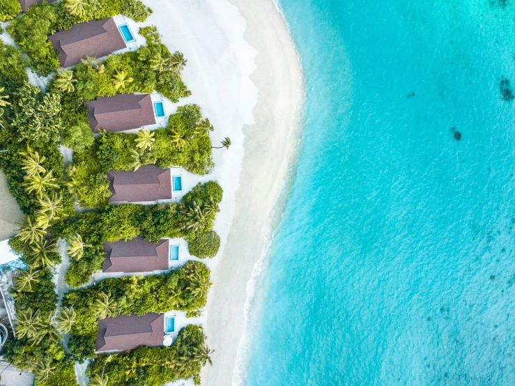 a group of beach cabins with small boats on the water