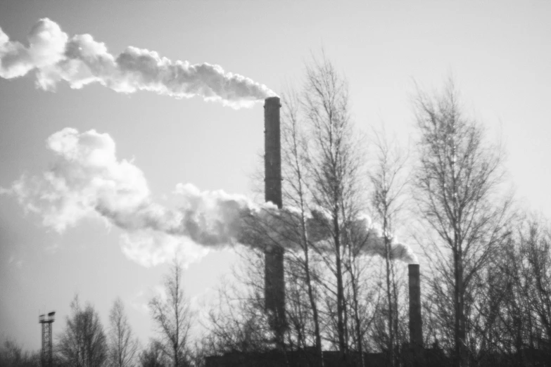 some smokestacks billowing from a row of pipes