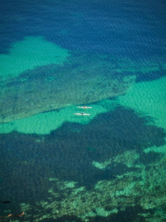 two airplanes are flying close to each other in the blue water