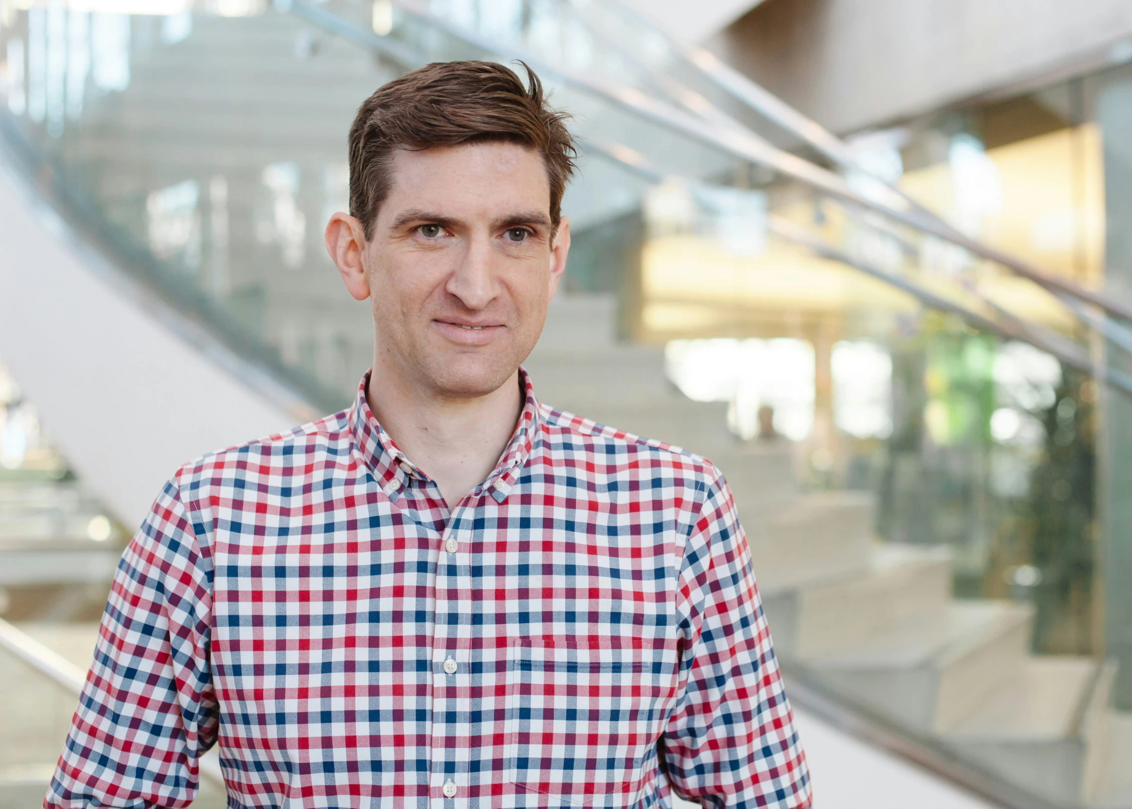 a man in plaid shirt standing by a staircase