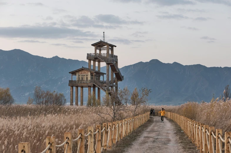 an old water tower in a field with mountains in the background