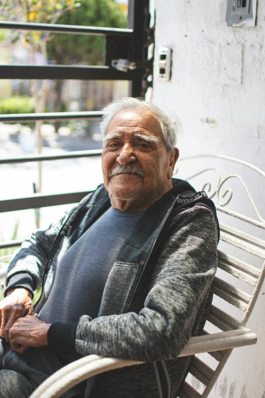 an elderly man with an angry look sits on a bench