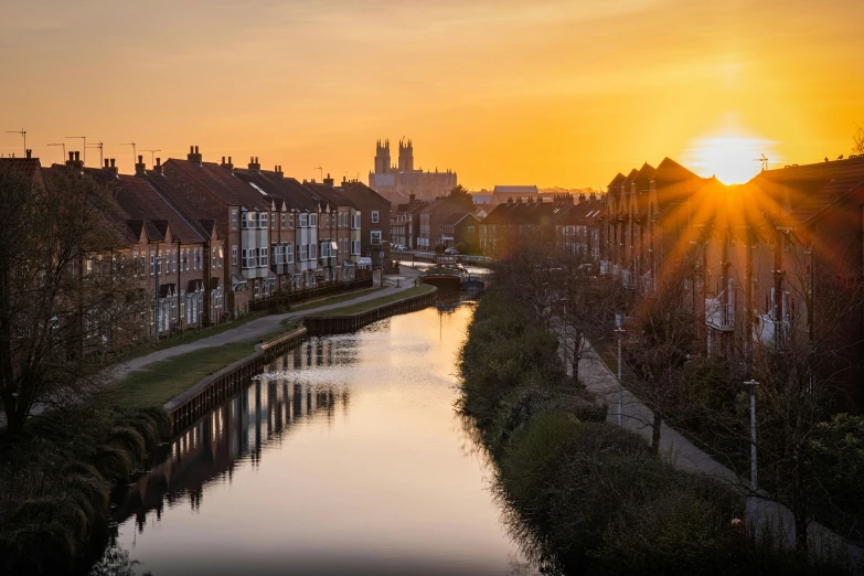 the sun rises over a river in a city