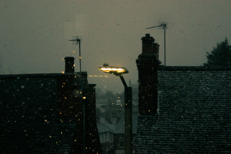 a night view shows a traffic signal, and residential rooftops