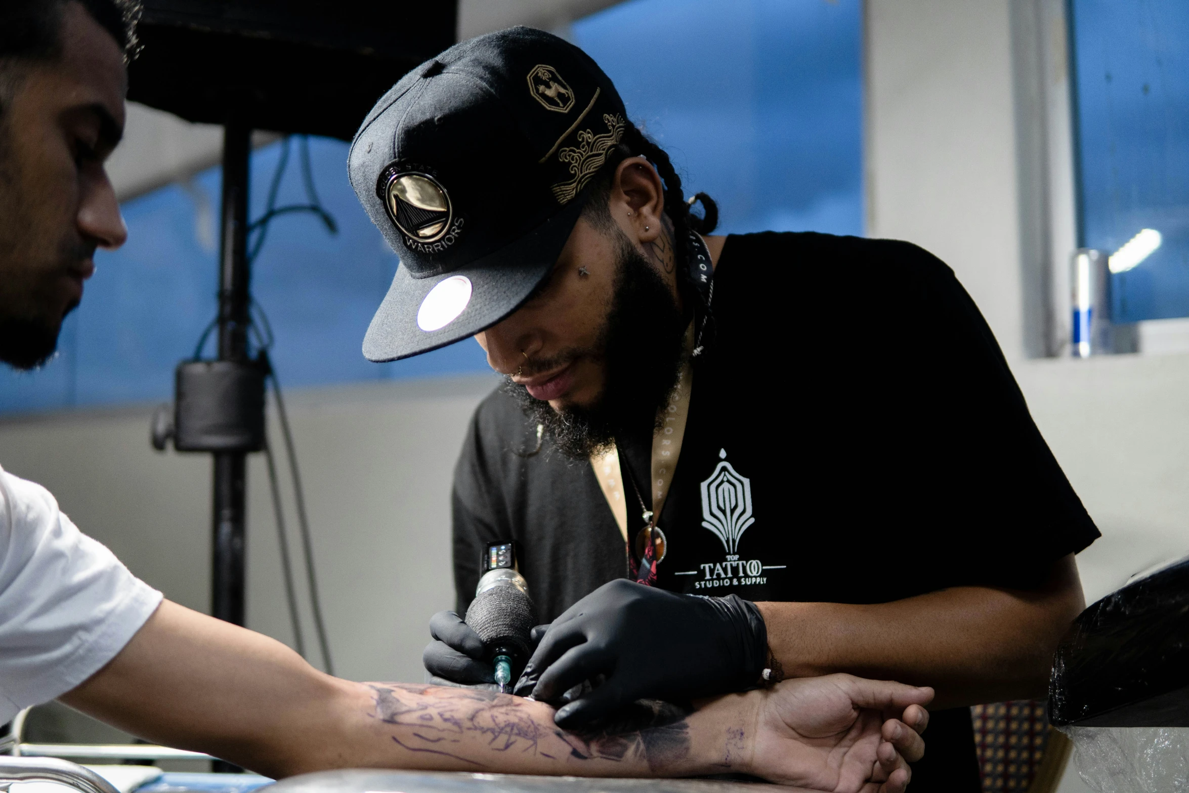 the man is working on his tattoo while another watches