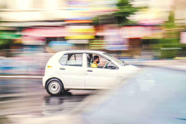 the man is driving in his small car on the street