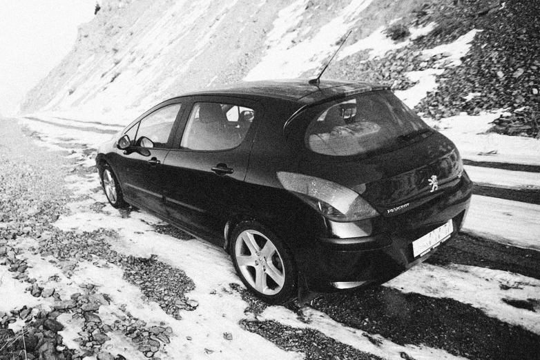 black and white image of a car driving down the road in the snow