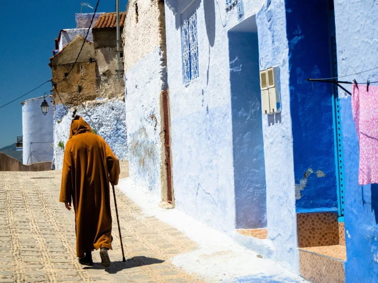 a person walking on the sidewalk with a stick in hand