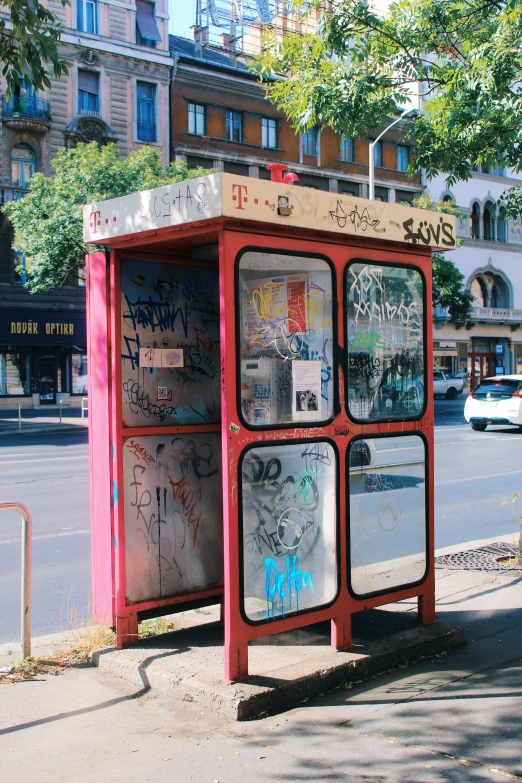 the red bus stop is covered with lots of graffiti