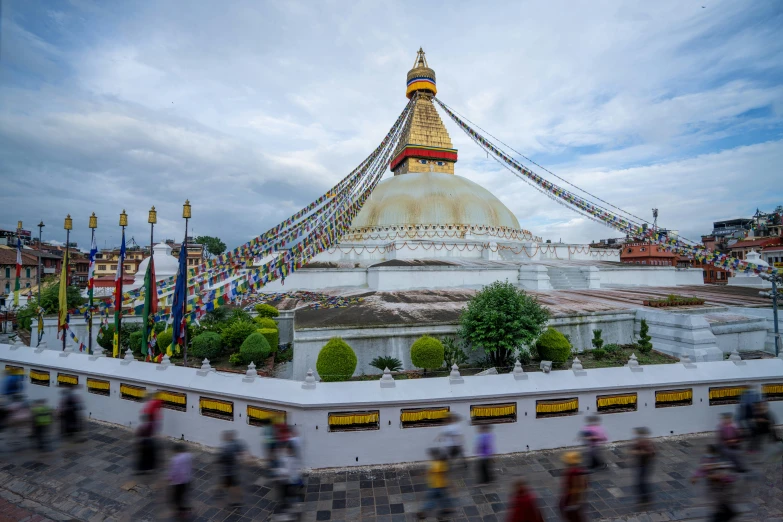 many people walking on the sidewalk and a big buddha statue