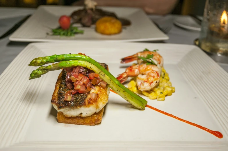 a white plate topped with seafood next to asparagus