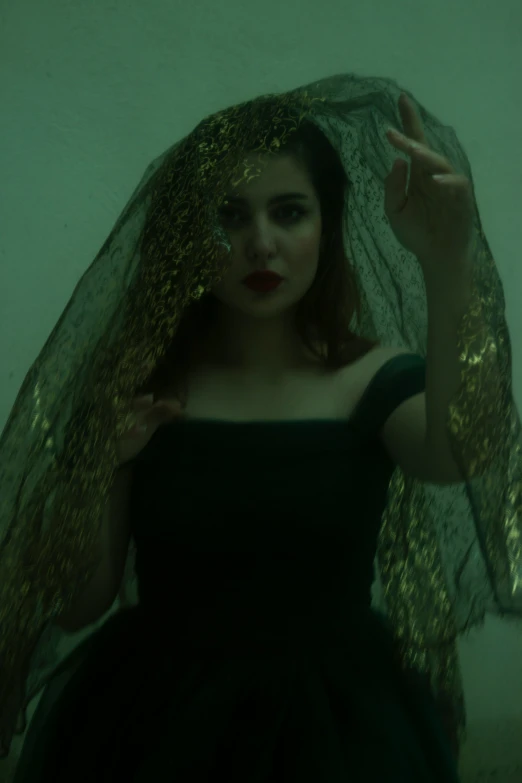 woman in black dress with gold veil and hand written on her face