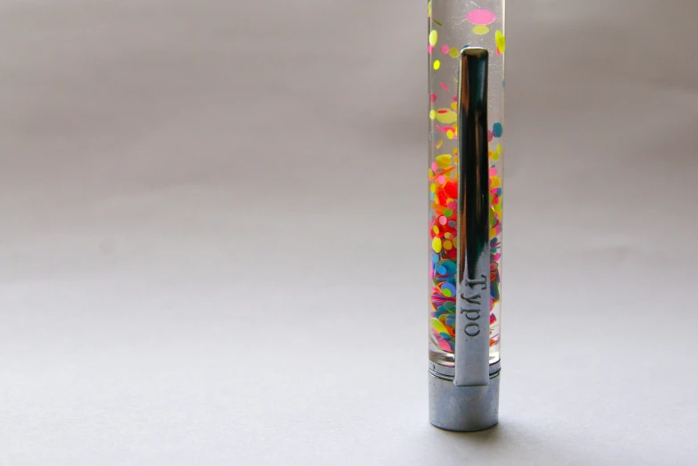 a black pen is painted with multi - colored sprinkles