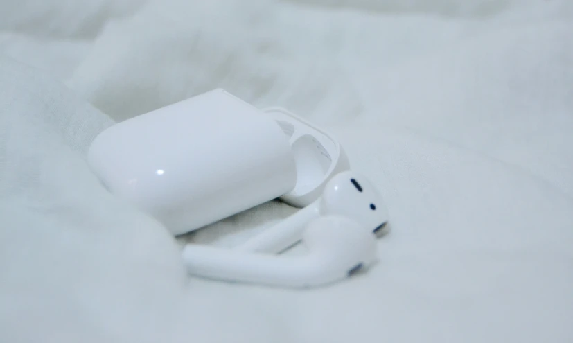 an apple wireless device and earphones sitting on a bed