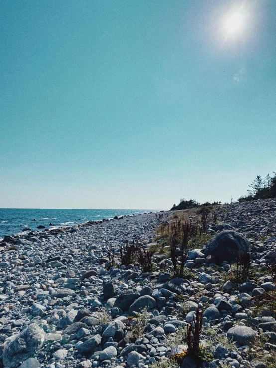 a sandy beach with rocks and a blue sky in the background